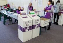 DHS Tallies Crumble Under Audit Election workers near ballot boxes in a polling station