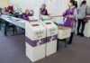 Election workers near ballot boxes in a polling station