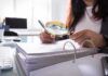 Person using a magnifying glass to review documents in a binder