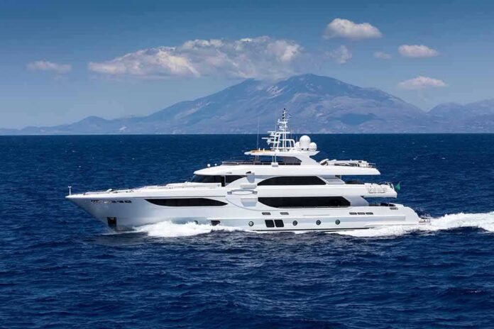 Luxury motor yacht cruising on blue sea with mountains in background