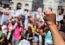 Raised fist in foreground at a crowded street protest