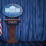 White House press briefing podium with U.S. flag and blue curtain
