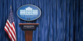 White House press briefing podium with U.S. flag and blue curtain