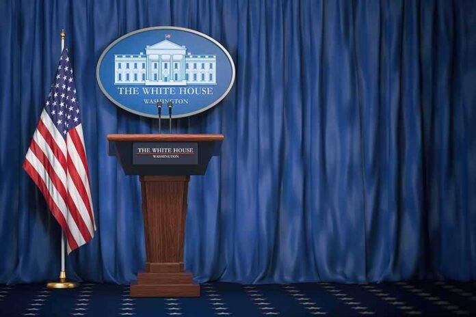shutterstock_1165119412-1 White House press briefing podium with U.S. flag and blue curtain