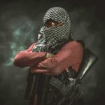 Terror Ties Named — One Name Missing armed person with face covered crossing arms