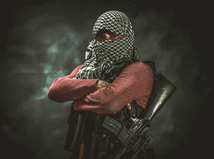 armed person with face covered crossing arms