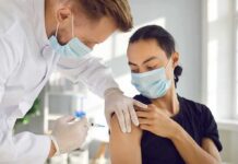 Healthcare worker giving a masked patient a vaccine in the upper arm