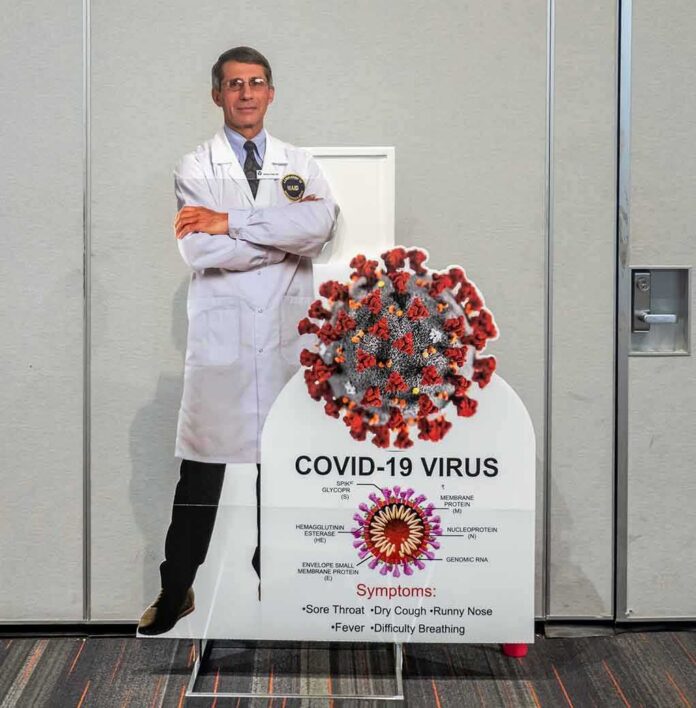 shutterstock_1949881045-1 Cardboard cutout of doctor with COVID-19 virus info display