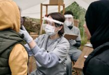 Toxic Sprays Under Fire in Ladera Healthcare worker in protective gear examines a patient at an outdoor clinic