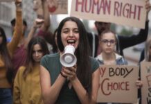 Universities Paralyzed — Jewish Students Exposed Young woman leading a protest with a megaphone