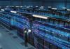 Technician with laptop in a large data center aisle