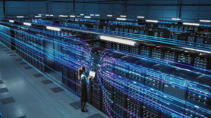 Technician with laptop in a large data center aisle