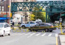 Police cars block a city intersection with yellow crime scene tape