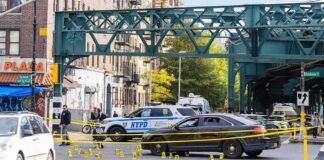 Police cars block a city intersection with yellow crime scene tape