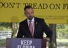 Spending Bloodbath Looms In Florida man in suit speaking at a podium outdoors