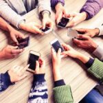 Hands around a table holding smartphones