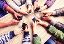 Hands around a table holding smartphones