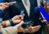 businessperson in suit surrounded by microphones and recorders