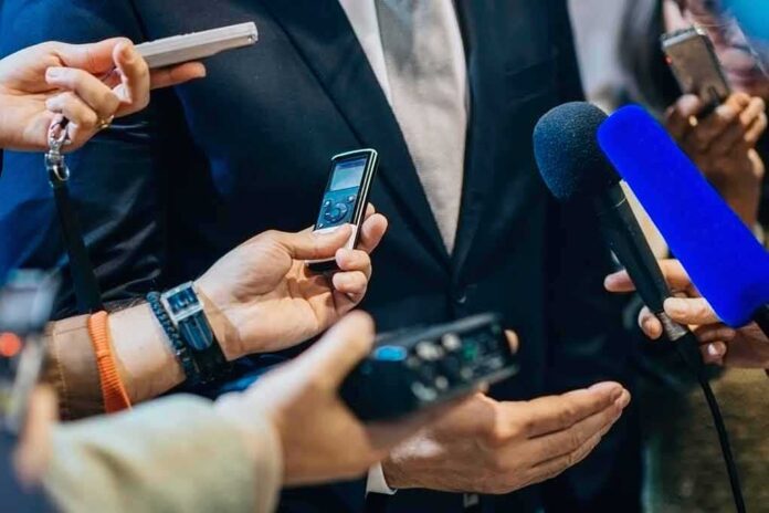 shutterstock_471987556-10 businessperson in suit surrounded by microphones and recorders