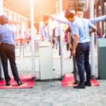 Security officers screen people at walk-through metal detectors