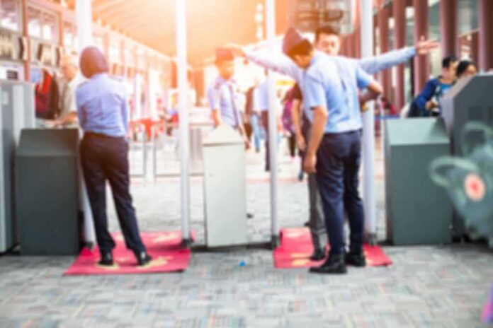Security officers screen people at walk-through metal detectors