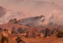 Wildfire burns on hillside near suburban homes