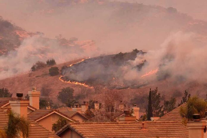 Wildfire burns on hillside near suburban homes