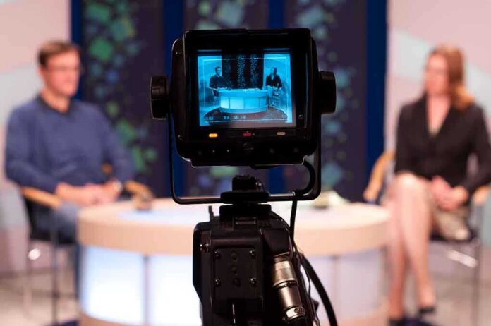 shutterstock_86885593-4 Camera focused on a television studio interview with two seated hosts