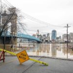 Flooded riverfront with bridge and city skyline