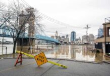 High Tides and Winds Flood New York Flooded riverfront with bridge and city skyline
