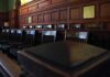 Holdout Juror Stops Everything Empty wooden jury box with numbered chairs