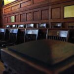 Holdout Juror Stops Everything Empty wooden jury box with numbered chairs