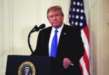 man at podium with microphone and US flag