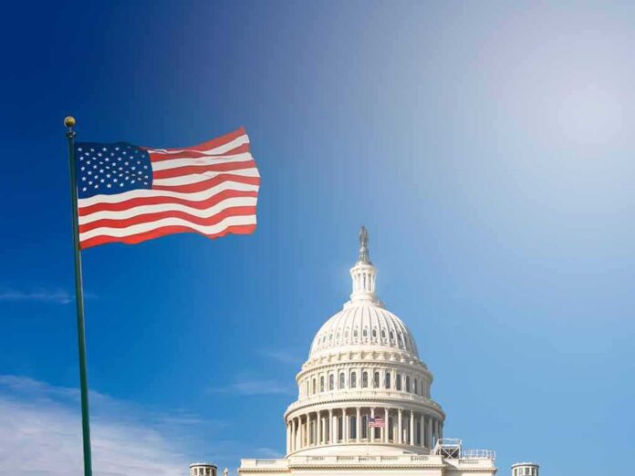 shutterstock_1345477700 American flag waves beside the U.S. Capitol dome