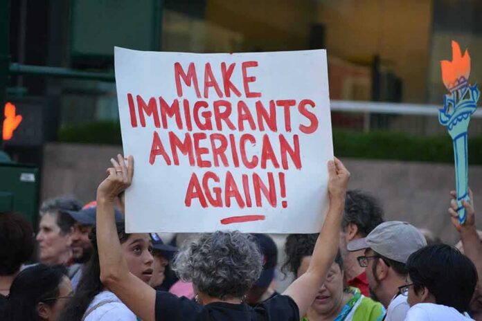 shutterstock_1449371015-8 Teddy Williams at a protest holding a sign reading 'Make Immigrants American Again'