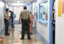 Corrections officers escort an inmate in a jail hallway
