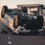 SUV Swept Away in Sudden Mudflow Overturned car on road with firefighters and ambulance