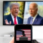 $10M Shock Wave Hits Texas Smartphone with ballot icon held before a TV showing two blurred politicians