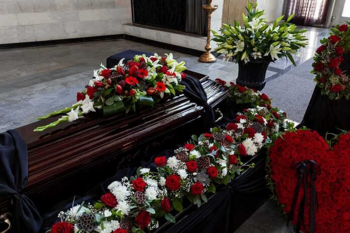 shutterstock_1869583603-5 Coffin with floral arrangements at a funeral service