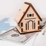 Fed Keeps Another Rate Hike Alive Wooden house model on money and contract papers