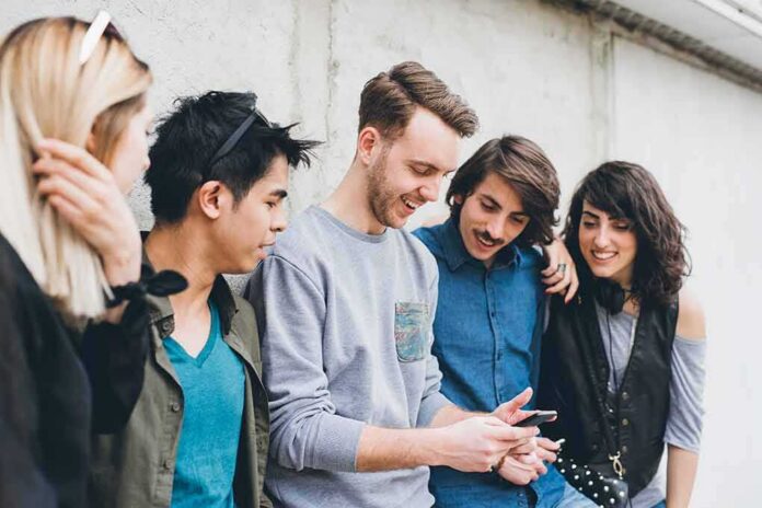 shutterstock_1908675214 Group of friends looking at a smartphone