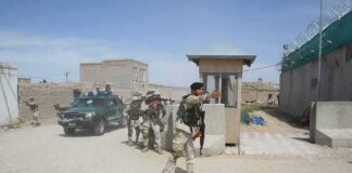 Armed soldiers patrol near a guard post outside a walled compound