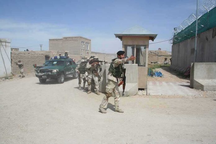 shutterstock_1931171399-2 Armed soldiers patrol near a guard post outside a walled compound