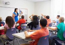 Teacher leading classroom discussion with students raising hands