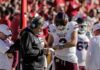 Mississippi State football coach and quarterback review play card on sideline