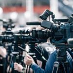 Boeing’s Giant Sub Hits A Wall Broadcast cameras on tripods at a press event