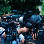 Britain’s Medal Queen Walks Away TV news cameras crowding together at an outdoor event