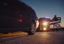 Police officer at patrol car during traffic stop at dusk