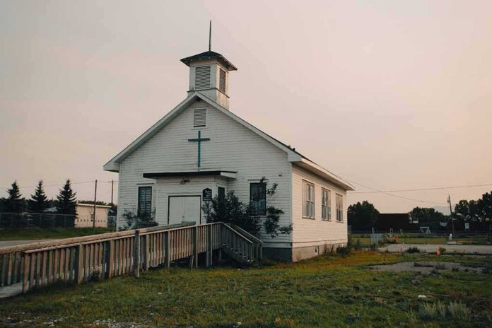Small white church with steeple and cross at sunset