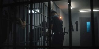 police officer at a jail cell with detainees behind bars